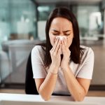 A picture of a woman with a kleenex trying to blow her nose