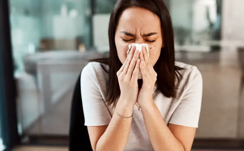 A picture of a woman with a kleenex trying to blow her nose