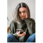 The Hidden Dangers of Ionized Air Purifiers Young woman looking concerned while reading about air purifiers on her phone