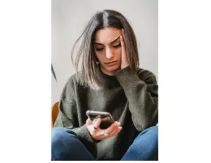 Young woman looking concerned while reading about air purifiers on her phone