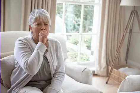 Person coughing while sitting near an air conditioner